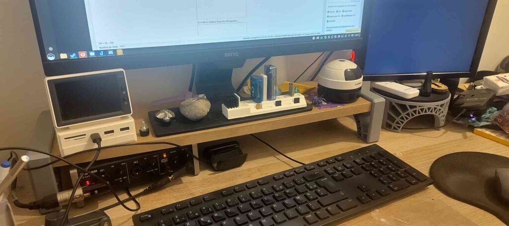 Réhausseur d'écran sur un bureau avec du matériel informatique autour.